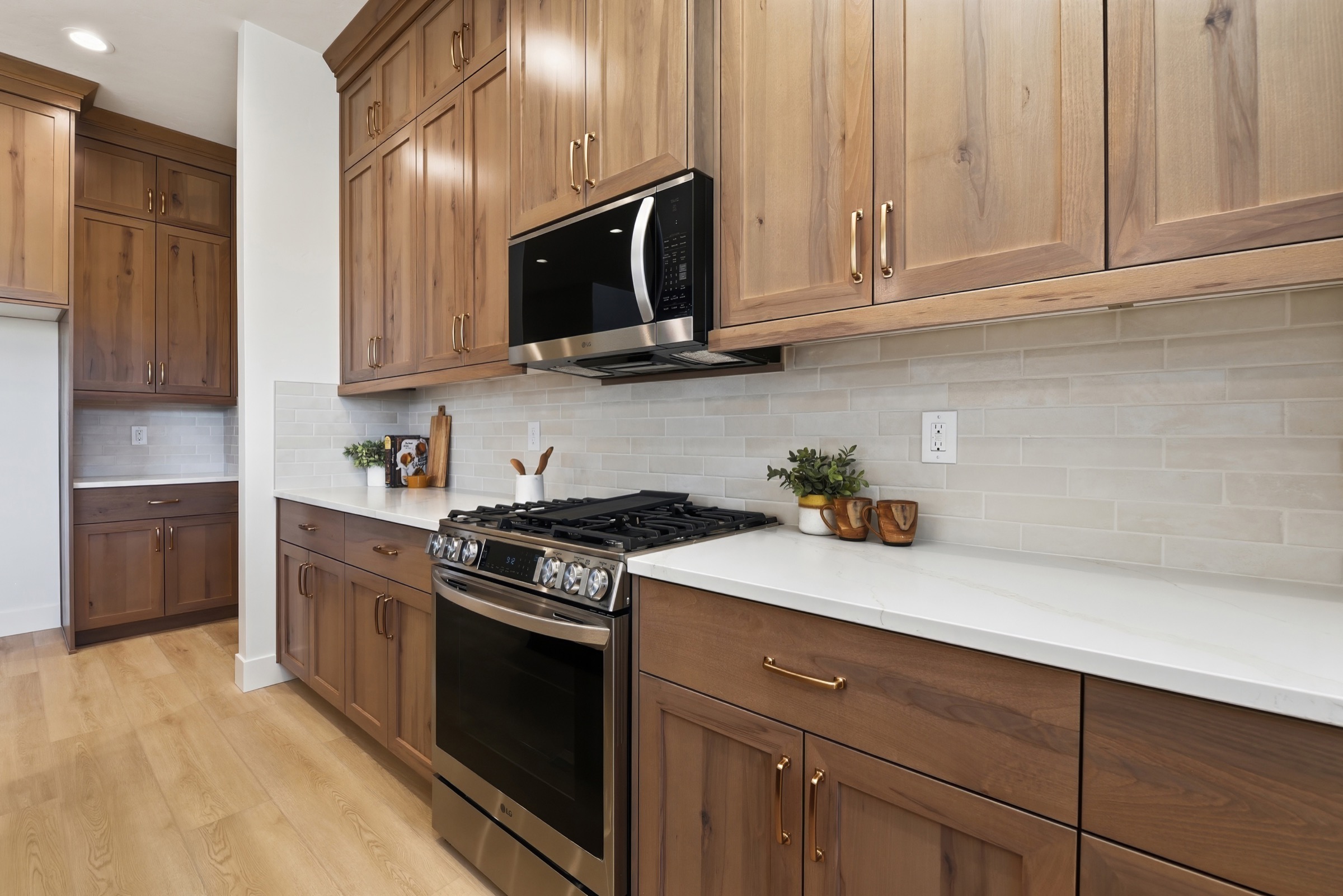 Warm walnut kitchen cabinetry with brass hardware and pale stone countertops