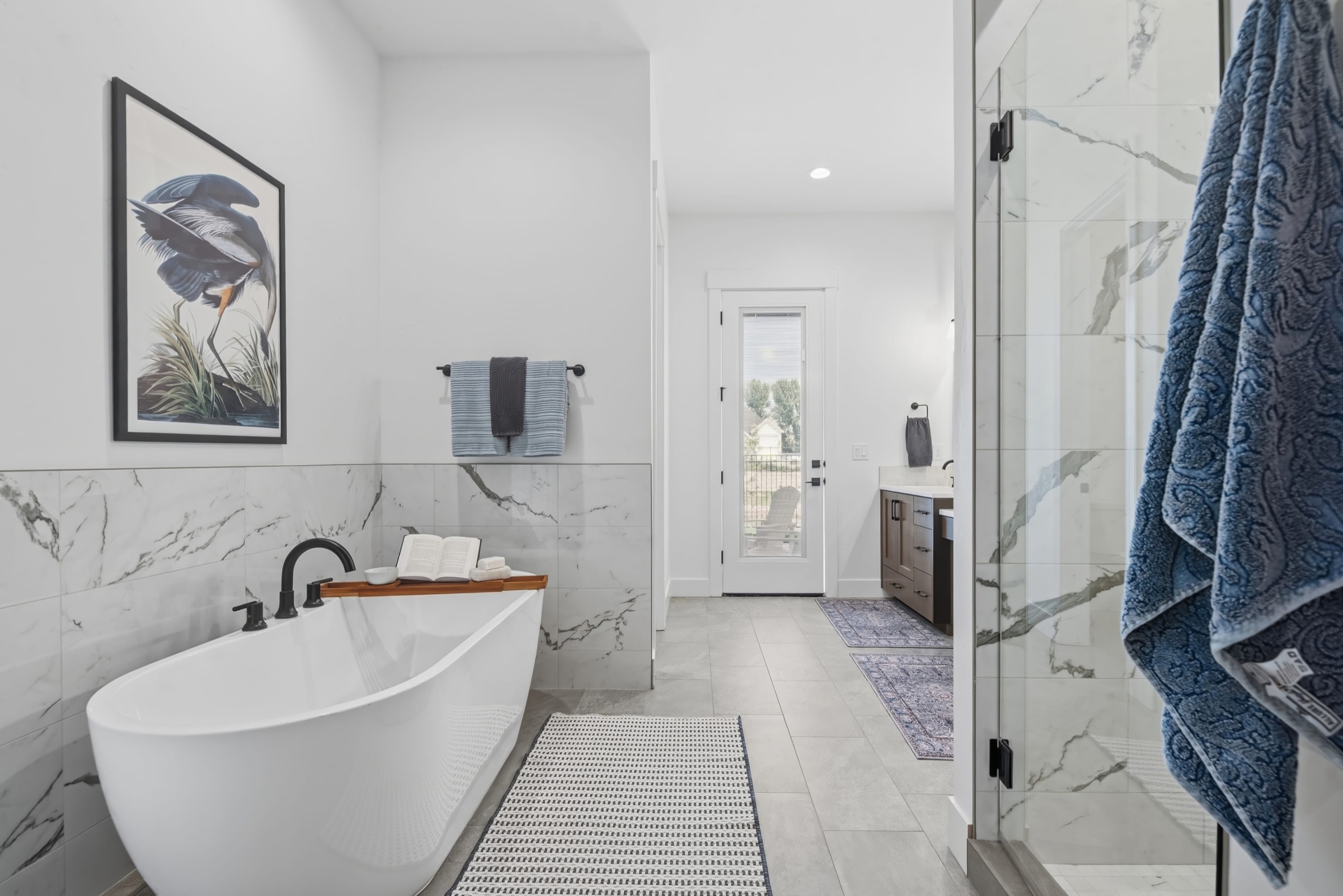 Airy primary bathroom with a freestanding tub and large-format marble-look tile